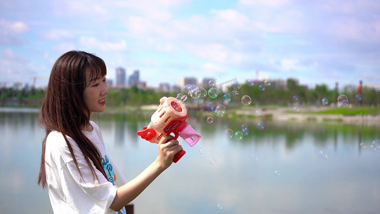 泡泡机摄影照片_晴朗天气女孩公园游玩泡泡机