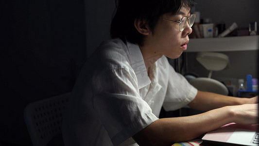 深夜灯光下伏案工作的男生特写实拍