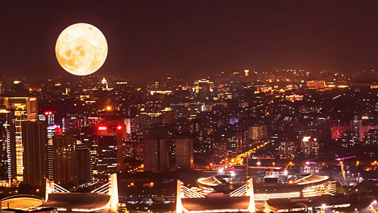中秋月圆摄影照片_暖色满月中秋城市夜景夜晚月亮城市中秋节赏月摄影图配图