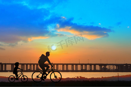 春节出行海报摄影照片_父亲节剪影晚上骑行人物户外自行车出行摄影图配图