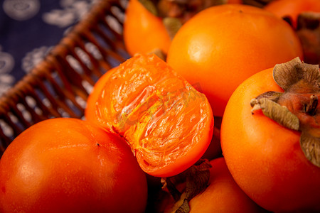 迷彩柿子摄影照片_美食秋季柿子室内篮子里摄影图配图