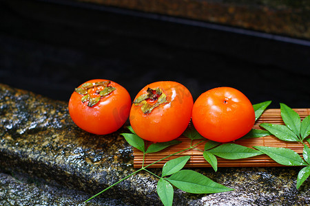 红色霜降摄影照片_水果秋季柿子红色柿子树叶摄影图配图