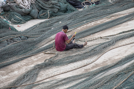 柬埔寨渔民与鸟摄影照片_补网的渔民下午渔民海岛为摄影图配图
