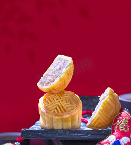 团圆饼摄影照片_传统美食中秋时节月饼吃月饼红色背景摄影图配图