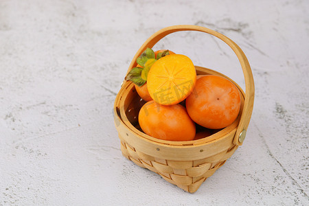秋摄影照片_新鲜美味水果篮子里的秋柿子摄影图配图