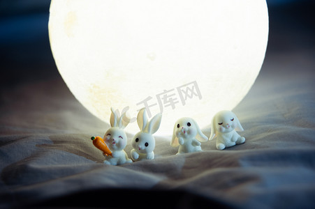 月亮玉兔摄影照片_中秋节夜晚月亮和玉兔在月亮下排队站着摄影图配图