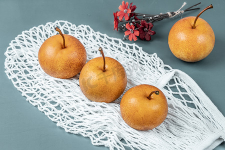 秋月摄影照片_白色网线袋与新鲜秋月梨健康水果摄影图配图