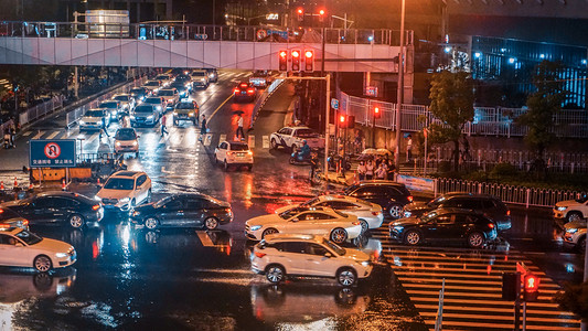 小雨中雨大雨摄影照片_交通路口雨夜十字路口道路城市摄影图配图