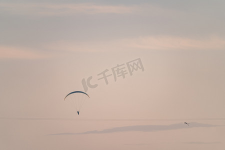 粉色降落伞摄影照片_郊外傍晚滑翔伞空中飞翔摄影图配图