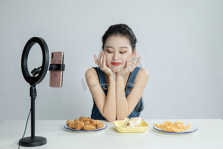 吃货动起来摄影照片_直播间看着美食的主播平拍摄影图配图