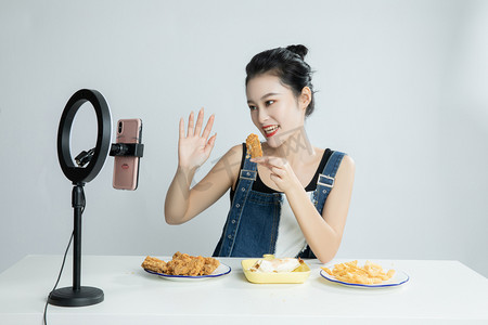 电商热卖款摄影照片_手拿鸡块在直播的美女平拍摄影图配图