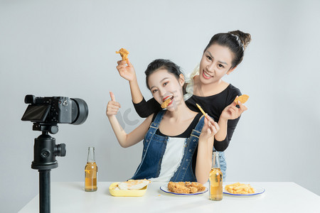 电商直播摄影照片_美食吃播白天两个美女直播吃炸鸡摄影图配图