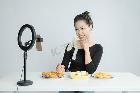 吃货节摄影照片_直播镜头前手拿美食微笑的主播平拍摄影图配图