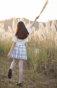 朝气摄影照片_手拿芦苇的女孩背影下午女孩芦苇无摄影图配图