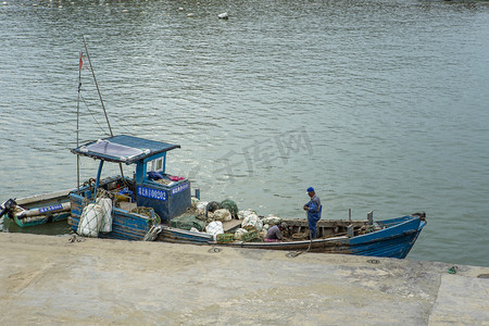 渔民打渔摄影照片_洞头岛海边补网的人下午补网海岛无摄影图配图