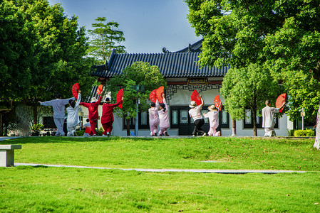 草摄影照片_白天户外跳舞团队在草地上排练摄影图配图