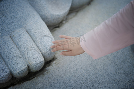 东莞观音山摄影照片_手摸佛脚的女孩下午手势寺庙无摄影图配图