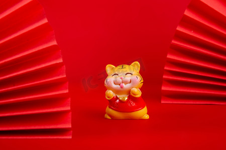 国画老虎摄影照片_春节白天一个老虎玩偶红色背景摆放摄影图配图