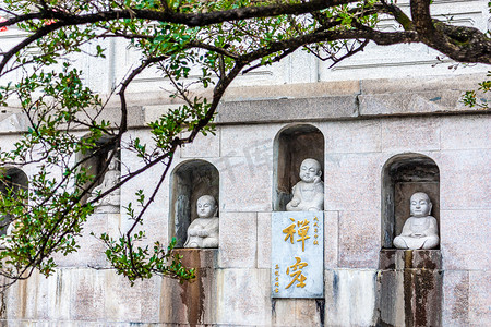 南京毗卢寺秋天绿树掩映下的石窟佛像特写摄影图配图