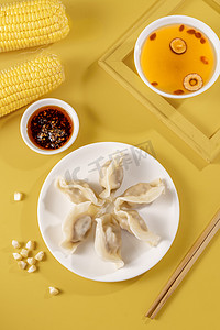 冬至水饺摄影照片_白色盘子里新鲜的玉米猪肉馅水饺摄影图配图