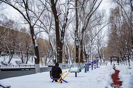 东北大雪百年一遇老人孤独雪景冬天背影静坐摄影图配图