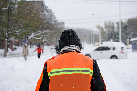 城市下雪摄影照片_城市雪中环卫工大街行走摄影图配图