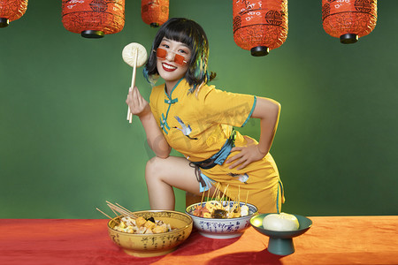 新中国风国潮摄影照片_国潮复兴白天叉着腰的旗袍美女室内用筷子夹起包子摄影图配图