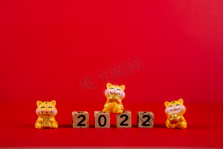 2022虎年背景摄影照片_春节2022三个卡通老虎红色背景摆放摄影图配图