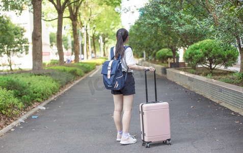 新生入学季摄影照片_美女开学拖箱子新生书包摄影图配图