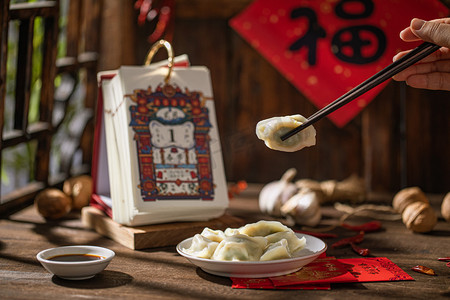 包饺子海报摄影照片_过年白天餐饮室内筷子夹饺子水饺摄影图配图