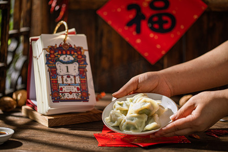过年白天端饺子的手户外端饺子摄影图配图