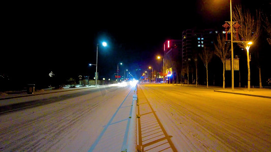 拍摄飘雪的夜晚街头缓慢行驶的车辆