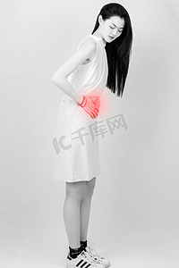 肚子痛摄影照片_一个青年女性捂着肚子疼痛的表情摄影图配图