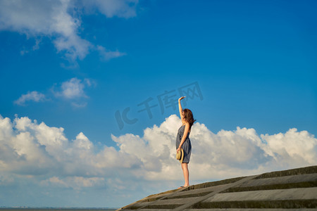 海岛夏季女生蓝天白云招手摄影图配图