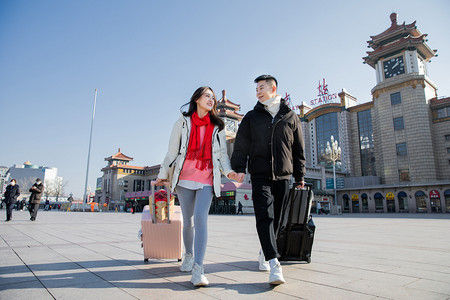 春运白天拉着行李箱的年轻美女火车站手拉手摄影图配图