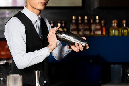 工作喝酒摄影照片_鸡尾酒晚上工作中的调酒师酒吧摇酒摄影图配图