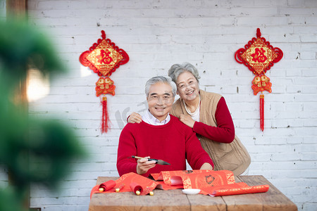 虎年摄影照片_春节奶奶拍爷爷在家写春联摄影图配图