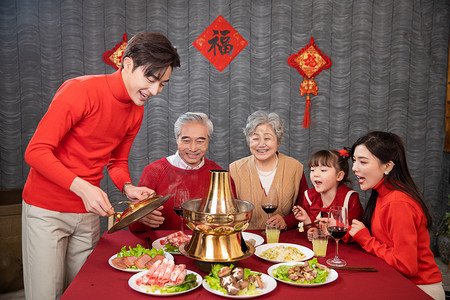 年夜饭一家人吃火锅喝红酒庆祝团圆摄影图配图