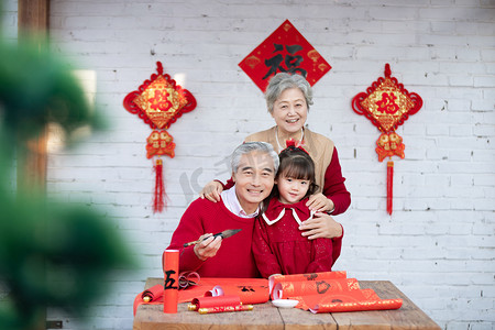 虎年新年喜庆摄影照片_大年三十爷爷奶奶教宝贝写春联摄影图配图