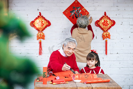 虎年新年喜庆摄影照片_春节爷爷在家教小女孩写对联摄影图配图