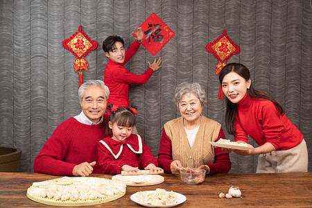 人物包饺子摄影照片_除夕爸爸贴福爷爷奶奶教孙女包饺子摄影图配图