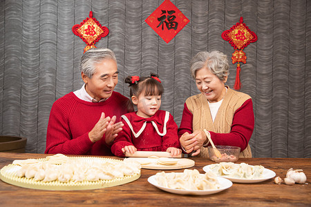 人物包饺子摄影照片_除夕爷爷奶奶和孙女一起包饺子摄影图配图