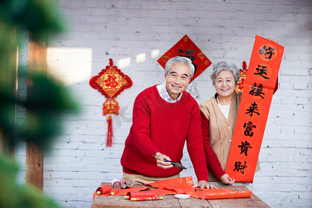 虎年新年喜庆摄影照片_春节爷爷写春联奶奶手拿对联摄影图配图