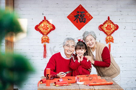 开心中国老人摄影照片_爷爷年年陪着小女孩写春联摄影图配图