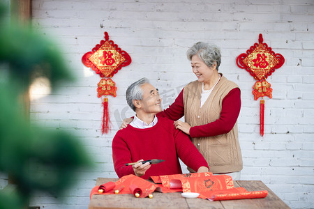 对联的人摄影照片_大年三十在家写春联的爷爷奶奶摄影图配图