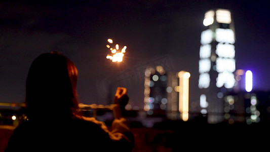 年会氛围道具摄影照片_城市夜晚女生放烟花虚化光影孤独