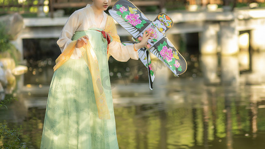 蝴蝶风筝插画摄影照片_拿风筝的女子下午女子公园公园摄影图配图