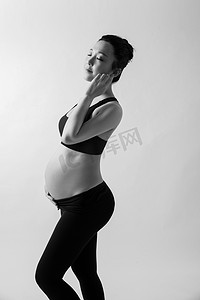 孕妈瑜伽摄影照片_孕婴白天孕妇室内闭眼睛摸肚子摄影图配图