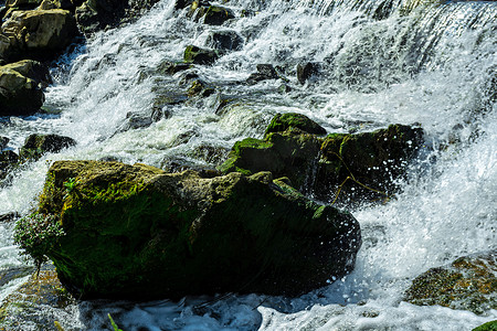 冲击力强摄影照片_湍急的河流冲击石头激起水花摄影图配图
