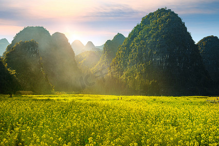风景摄影照片_万峰林山脚下盛开的油菜花摄影图配图